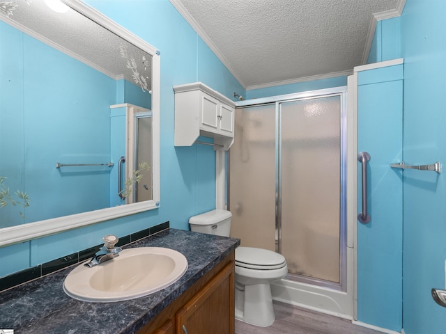 bathroom with ornamental molding, toilet, a textured ceiling, a shower stall, and wood finished floors