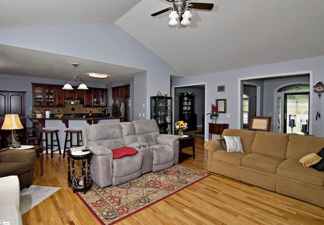 living area featuring light wood-style floors, vaulted ceiling, and a ceiling fan