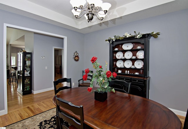 dining area featuring a chandelier, baseboards, and wood finished floors