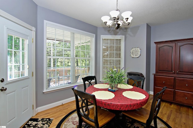 dining space with light wood finished floors, an inviting chandelier, and baseboards