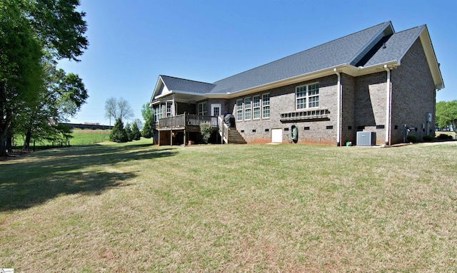 rear view of house featuring cooling unit, brick siding, stairs, and a lawn