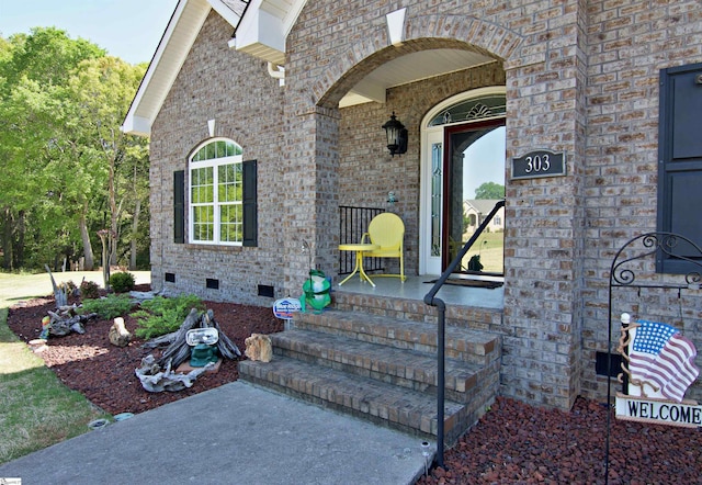 property entrance featuring brick siding, a porch, and crawl space