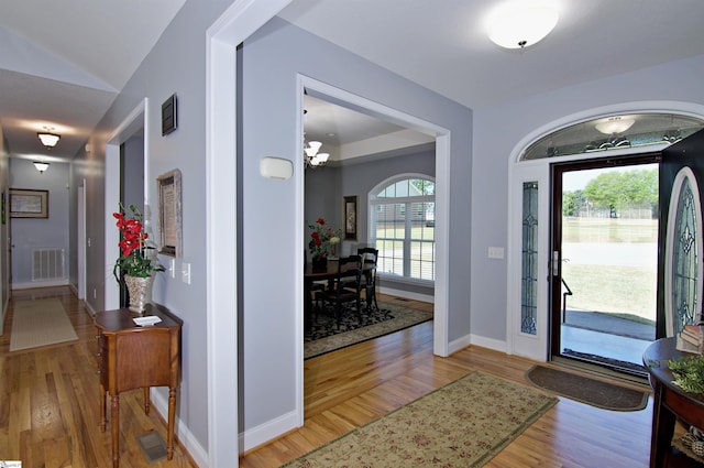 entryway with visible vents, baseboards, light wood finished floors, and an inviting chandelier