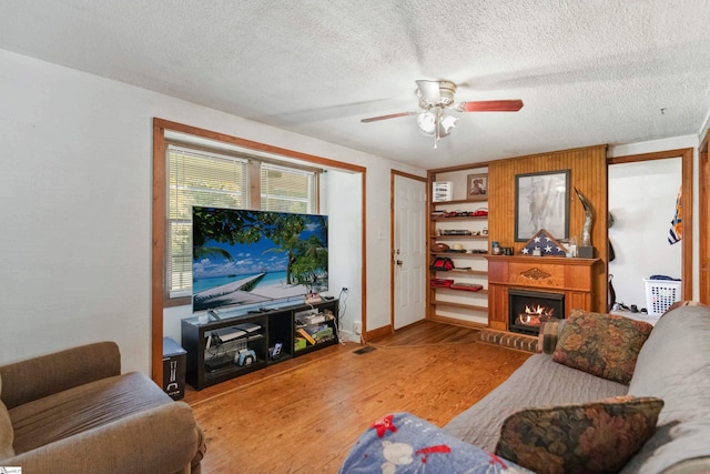 525 Firetower Rd, Williamston, SC 29697 - living area featuring a lit fireplace, a textured ceiling, a ceiling fan, wood finished floors, and baseboards