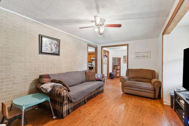 525 Firetower Rd, Williamston, SC 29697 - living area featuring brick wall, light wood-style floors, a textured ceiling, and a ceiling fan