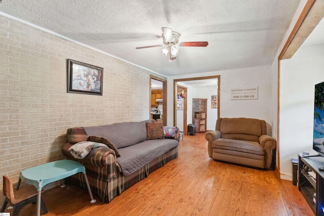 525 Firetower Rd, Williamston, SC 29697 - living area featuring light wood-style flooring, a ceiling fan, brick wall, and a textured ceiling