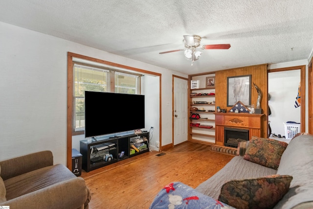 525 Firetower Rd, Williamston, SC 29697 - living room featuring baseboards, a textured ceiling, a fireplace with raised hearth, ceiling fan, and wood finished floors