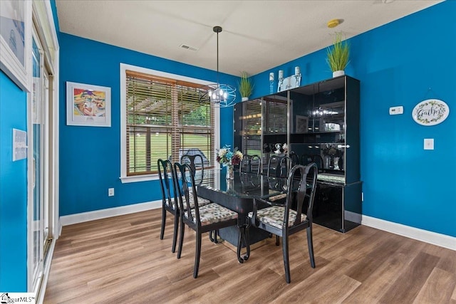 dining room with a chandelier, wood finished floors, baseboards, and visible vents