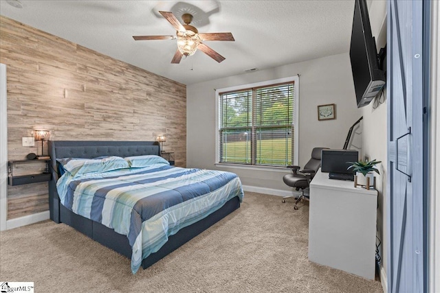 bedroom with baseboards, an accent wall, a ceiling fan, wooden walls, and light carpet