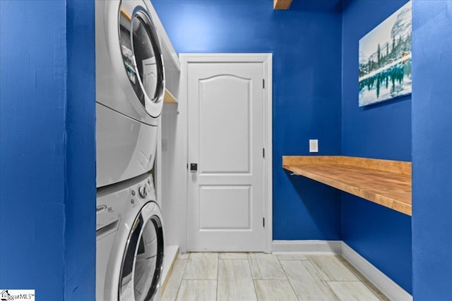 washroom featuring baseboards, stacked washer and clothes dryer, and laundry area