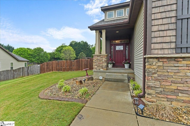 entrance to property featuring stone siding, fence, and a lawn