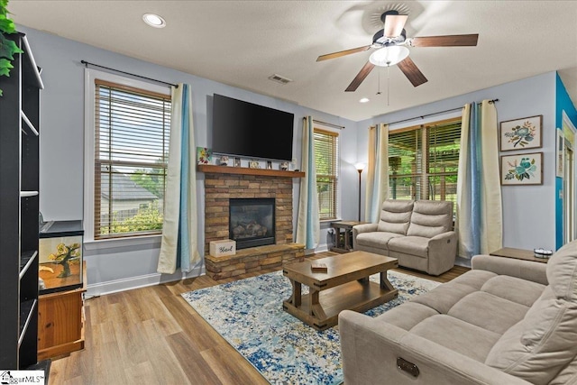 living area featuring plenty of natural light, a fireplace, visible vents, and ceiling fan