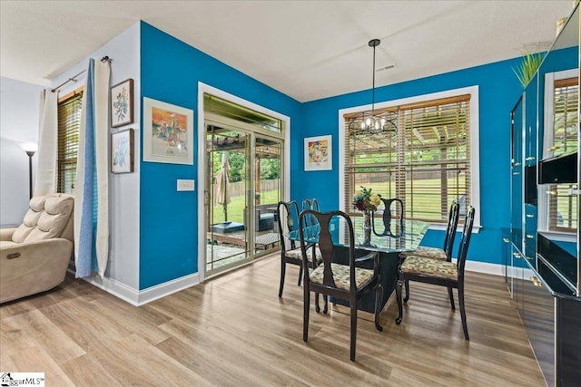dining space with baseboards, a notable chandelier, wood finished floors, and a healthy amount of sunlight