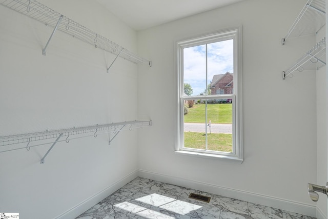 spacious closet featuring visible vents and marble finish floor