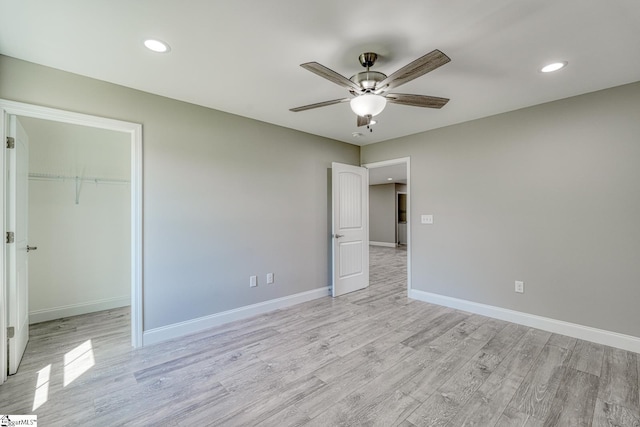 unfurnished bedroom with light wood-style floors, baseboards, and a walk in closet