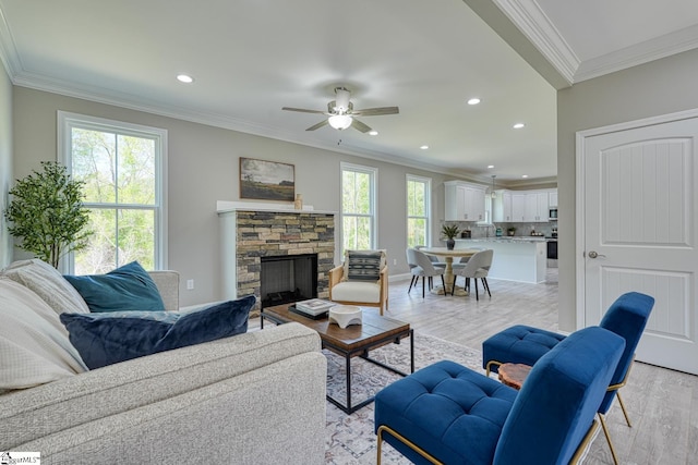 living room featuring a fireplace, recessed lighting, crown molding, light wood-style floors, and ceiling fan