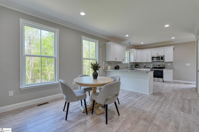 dining area with crown molding, baseboards, and visible vents