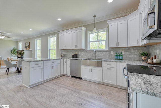 kitchen featuring tasteful backsplash, white cabinets, appliances with stainless steel finishes, a peninsula, and crown molding