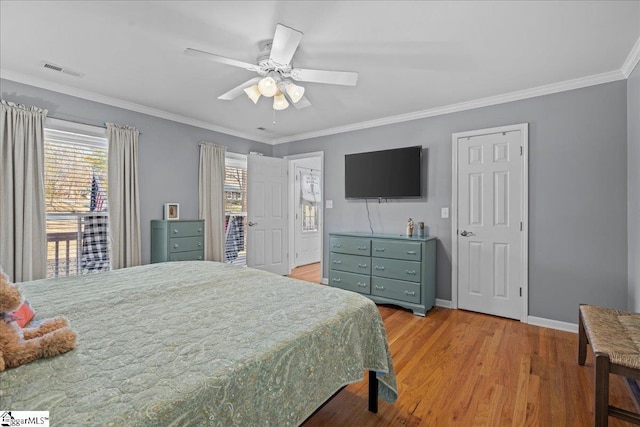bedroom with baseboards, ornamental molding, a ceiling fan, visible vents, and wood finished floors