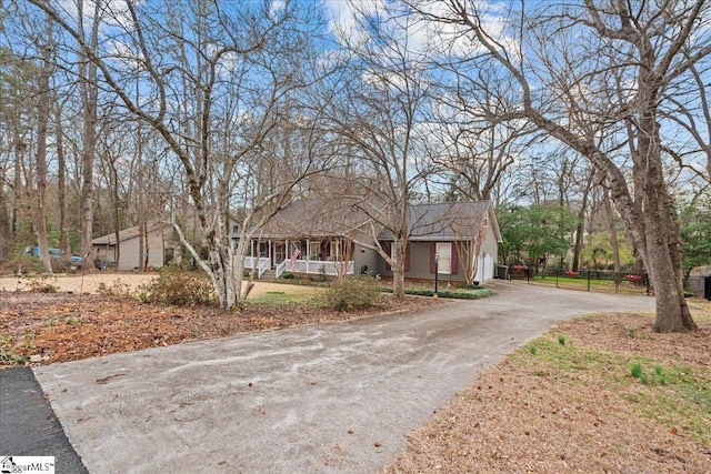 ranch-style house featuring a porch, fence, and aphalt driveway