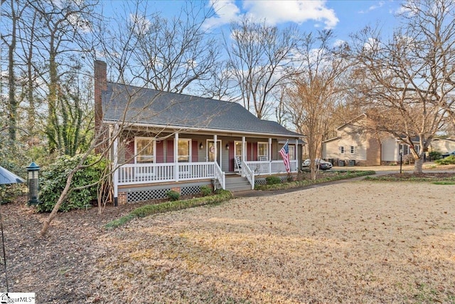 view of front of home featuring roof with shingles, a porch, and a chimney