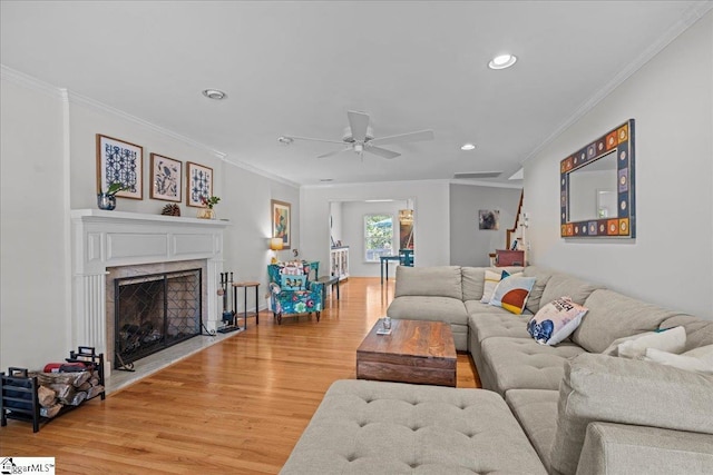 living room featuring light wood-style flooring, crown molding, a ceiling fan, and recessed lighting