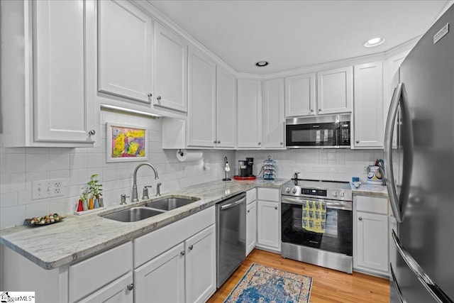 kitchen with tasteful backsplash, white cabinetry, a sink, and appliances with stainless steel finishes