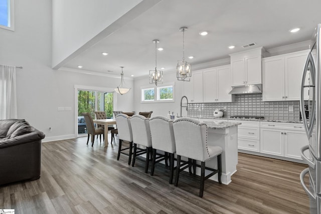 901 Whitemarsh Ave, Simpsonville, SC 29680 - kitchen featuring light stone countertops, a breakfast bar, appliances with stainless steel finishes, under cabinet range hood, and decorative backsplash