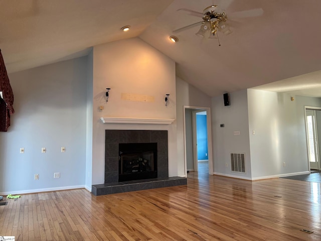 unfurnished living room featuring baseboards, visible vents, hardwood / wood-style floors, ceiling fan, and a tile fireplace