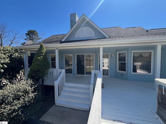 rear view of house featuring a chimney and covered porch