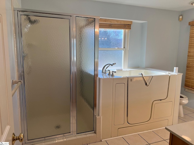 bathroom featuring toilet, tile patterned floors, washer / dryer, a stall shower, and a garden tub