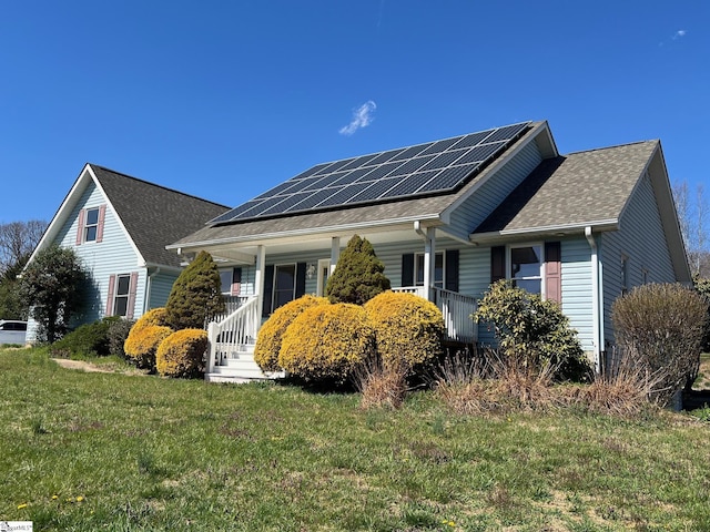 view of home's exterior with a porch, roof with shingles, a yard, and solar panels