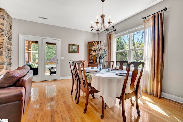dining space featuring a chandelier, light wood-type flooring, baseboards, and visible vents