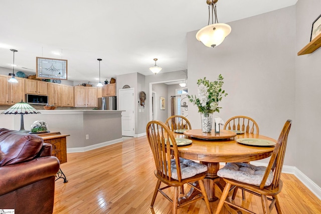 dining space featuring baseboards and light wood finished floors