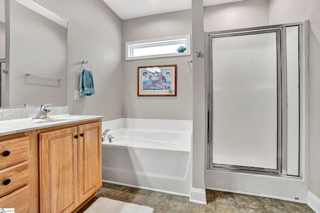 bathroom featuring a stall shower, a garden tub, vanity, and baseboards