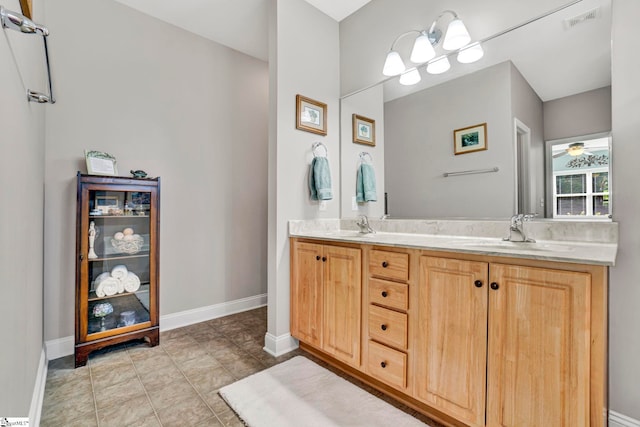 bathroom featuring baseboards, double vanity, a sink, and visible vents