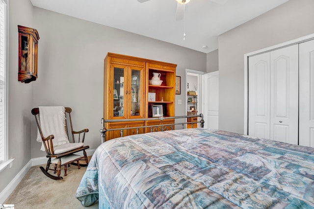 bedroom with light carpet, a closet, baseboards, and ceiling fan