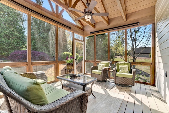 sunroom featuring beamed ceiling, ceiling fan, and plenty of natural light