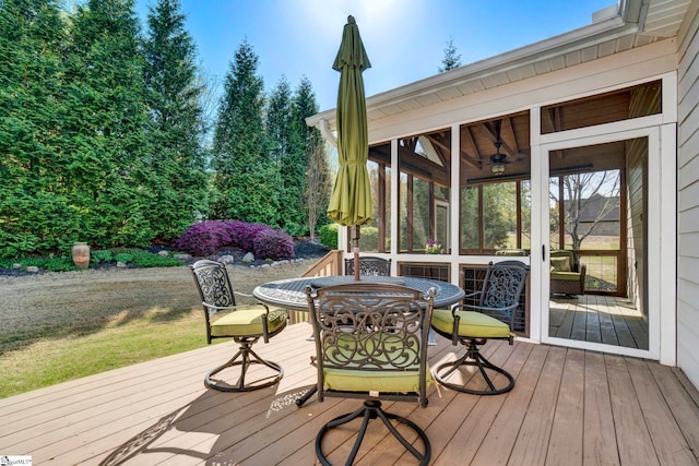 wooden deck featuring outdoor dining area and a sunroom