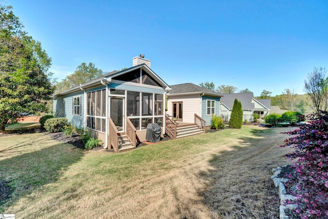 rear view of property with a yard, a sunroom, and a chimney