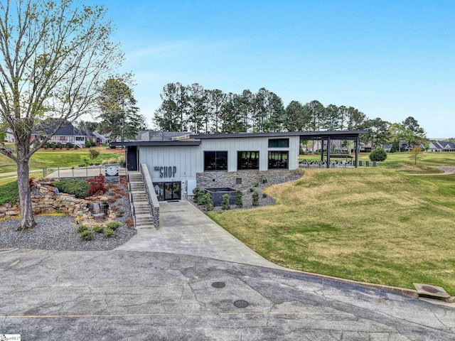 view of front facade featuring concrete driveway, stairway, and a front lawn
