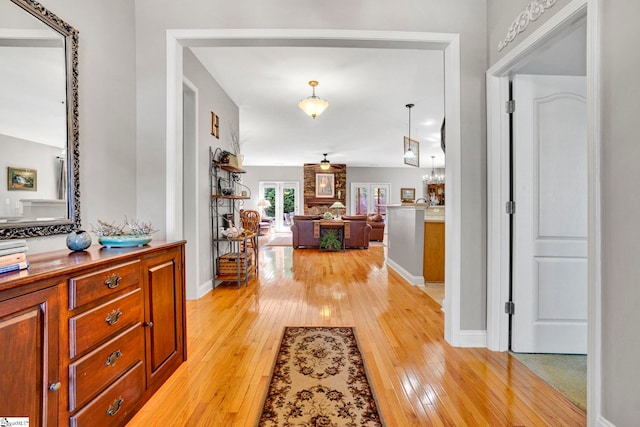 hall with light wood-style flooring and baseboards