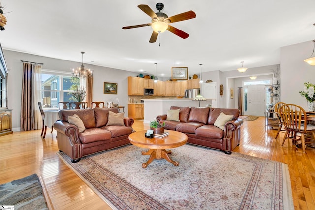 living area featuring light wood-type flooring and ceiling fan with notable chandelier