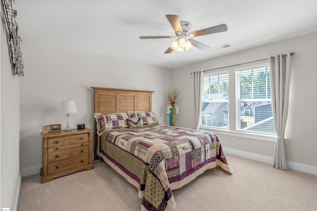 bedroom featuring visible vents, baseboards, ceiling fan, and light carpet
