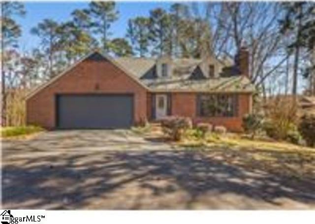 cape cod house with an attached garage and driveway