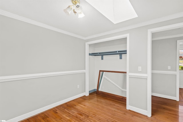 unfurnished bedroom featuring hardwood / wood-style flooring, baseboards, ornamental molding, and a skylight