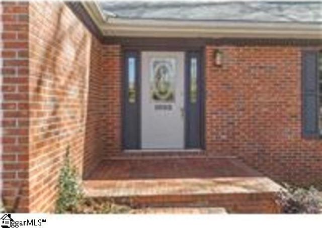 view of exterior entry featuring brick siding