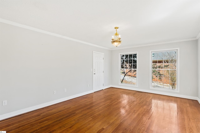 spare room with baseboards, an inviting chandelier, crown molding, and wood finished floors