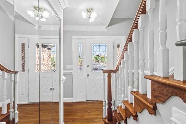 foyer with a chandelier, stairway, a textured ceiling, crown molding, and wood finished floors