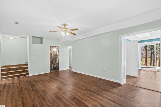 unfurnished living room with a ceiling fan, visible vents, wood finished floors, stairs, and baseboards